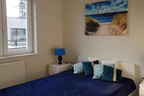 a bedroom with a bed with blue sheets and a window at Nowoczesny apartament przy Aquapark Reda in Reda