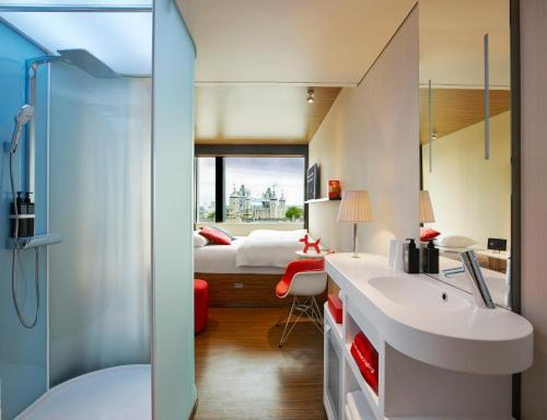 ein Badezimmer mit einem Waschbecken und ein Schlafzimmer mit einem Bett in der Unterkunft citizenM Tower of London in London