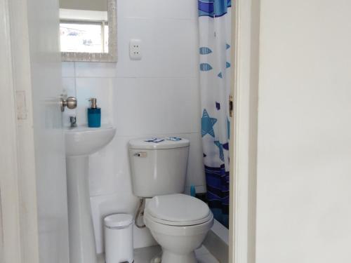 La salle de bains blanche est pourvue de toilettes et d'un lavabo. dans l'établissement Hospedaje de Lidia, à Lima
