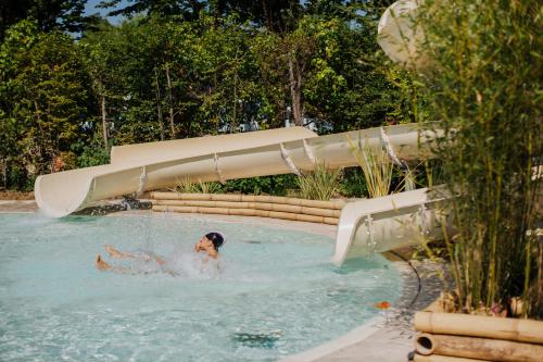 a dog swimming in a pool with a water slide at Camping Sabbiadoro in Lignano Sabbiadoro