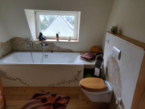 a bathroom with a tub and a toilet and a window at Maisonette Pablo in Gummersbach