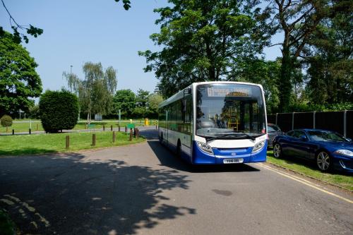 a blue and white bus driving down a street at Holiday Inn London - Gatwick Airport by IHG in Horley