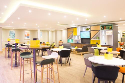a restaurant with tables and chairs and a kitchen at Holiday Inn London - Gatwick Airport by IHG in Horley