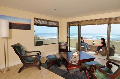two people sitting in a living room with a view of the ocean at Beach Hotel Swakopmund in Swakopmund