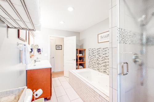La salle de bains blanche est pourvue d'une baignoire et d'une douche. dans l'établissement Livin On Tahoe Time, à South Lake Tahoe