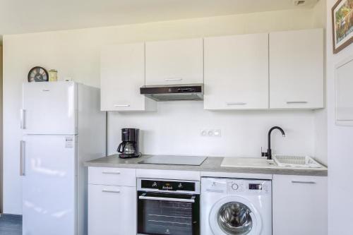 a kitchen with white cabinets and a washer and dryer at Le Nominoë - Studio à Lampaul-Plouarzel in Lampaul-Plouarzel