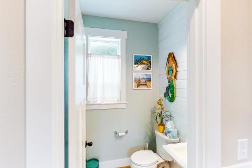 a bathroom with a white toilet and a window at Mermaids Grotto in Lincoln City