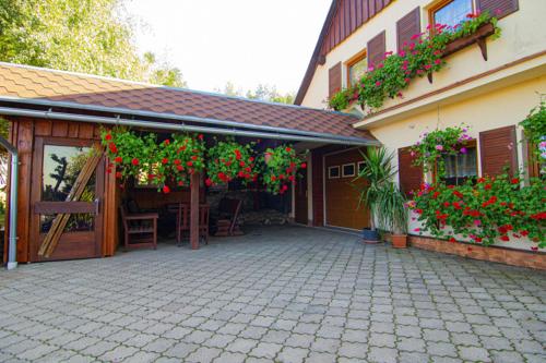 a house with a patio with red flowers on it at Pension Ivanka in Jestrabi V Krkonosich