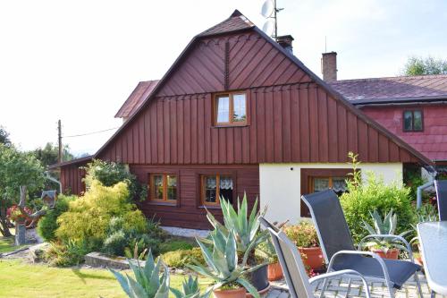 a red house with chairs and plants in front of it at Pension Ivanka in Jestrabi V Krkonosich