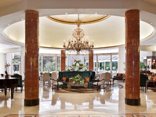 een lobby met een kroonluchter en tafels en stoelen bij InterContinental Madrid, an IHG Hotel in Madrid