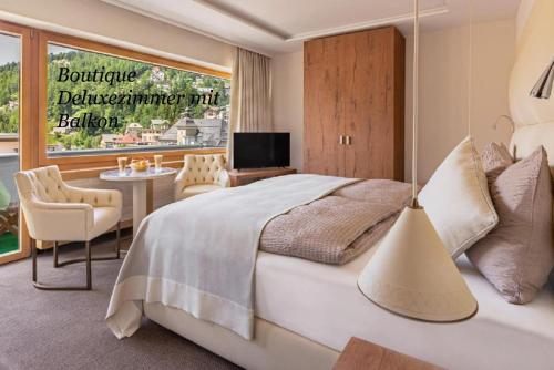 a bedroom with a bed and a table and a television at Hotel Arte in St. Moritz