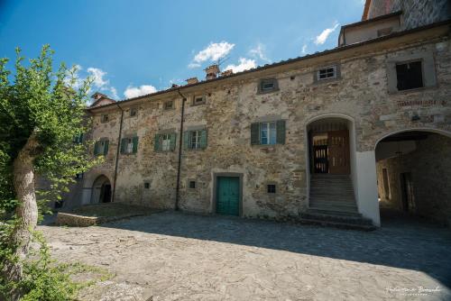 an old stone building with a green door and a courtyard at Castello di Sarna in Chiusi della Verna