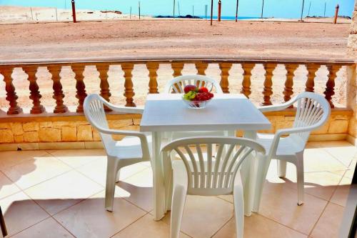 - une table et des chaises blanches avec un bol de fruits sur le balcon dans l'établissement Comfortable and spacious apartment with ocean views of Cabral beach, à Sal Rei