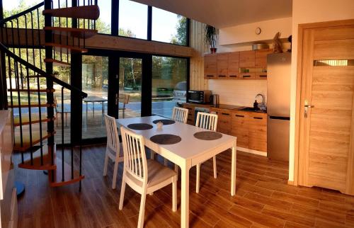 uma cozinha com uma mesa e cadeiras brancas e um frigorífico em Zakątek Bór, nowoczesne domki nad rzeką em Bór