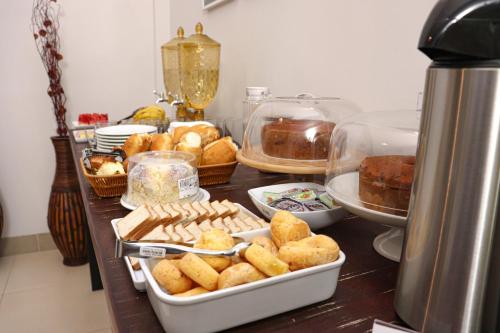 a table with trays of bread and pastries on it at Hotel Neblina in Araguaína