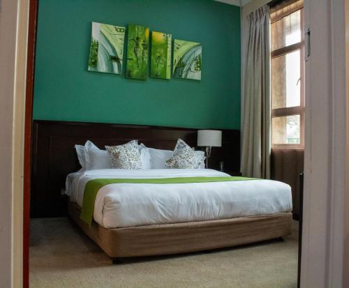 a bedroom with a large bed with a green wall at MalVille Boutique Hotel in Lilongwe