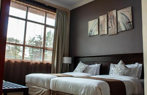 a bedroom with two beds and a window at MalVille Boutique Hotel in Lilongwe