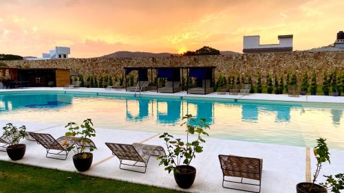 a swimming pool with chairs and a sunset in the background at Hotel Boutique Matea Inn in Ixtapan de la Sal