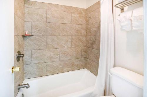 a bathroom with a shower with a tub and a toilet at Hotel Eastin Atchison in Atchison