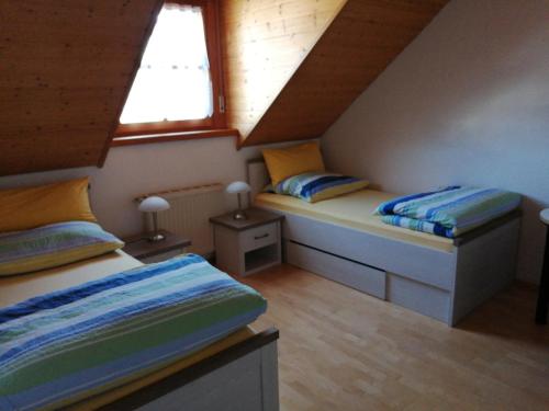 two beds in a attic room with two windows at FeWoDeg in Deggendorf
