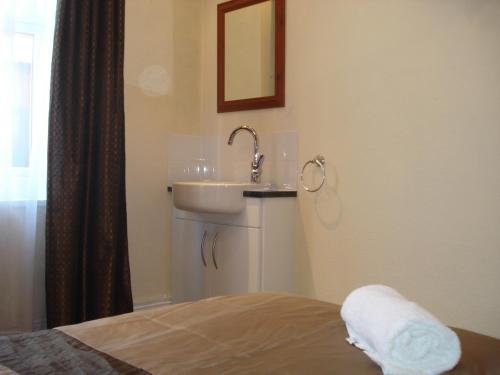 a bathroom with a sink and a bed at Masslink Guest House in Horley