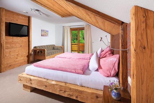a bedroom with a wooden bed with pink pillows at Gästehaus Anfanglehen in Ramsau