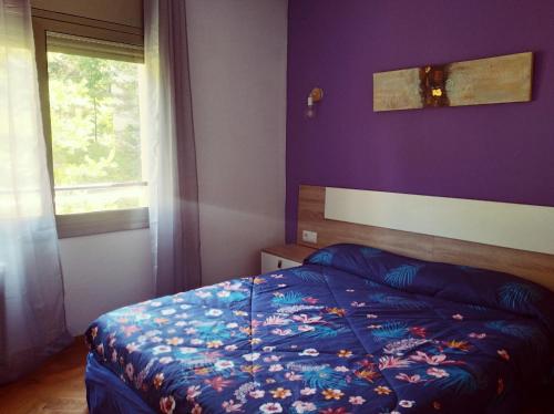 1 dormitorio con cama y pared púrpura en Apartamento en la Molina en La Molina Alp