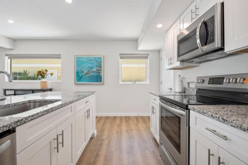 a kitchen with white cabinets and stainless steel appliances at Escape Casey Key in Nokomis