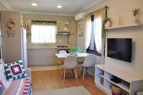 a living room with a kitchen and a table with chairs at Apartamento Florido Centro Gramado in Gramado