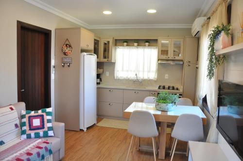 a kitchen with a table and chairs and a refrigerator at Apartamento Florido Centro Gramado in Gramado