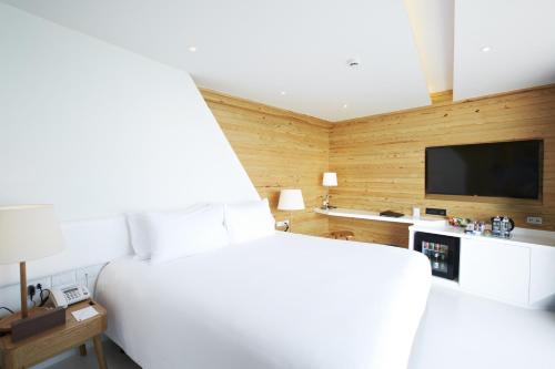 a bedroom with a white bed and a flat screen tv at Centara Q Resort Rayong in Mae Pim