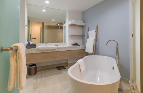 a bathroom with a tub and a large mirror at Centara Ao Nang Beach Resort & Spa Krabi in Ao Nang Beach