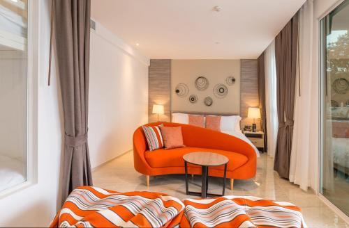 an orange couch and a bed in a room at Centara Ao Nang Beach Resort & Spa Krabi in Ao Nang Beach