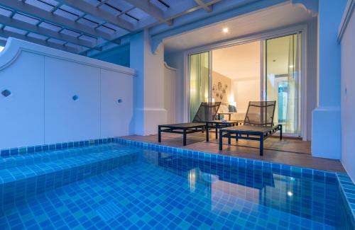 a pool in a villa with two chairs and a table at Centara Ao Nang Beach Resort & Spa Krabi in Ao Nang Beach