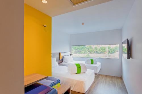 two beds in a room with yellow walls at COSI Pattaya Wong Amat Beach - SHA Plus Certified in Pattaya North