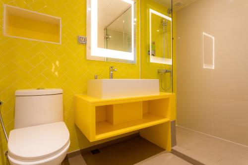 a yellow bathroom with a toilet and a sink at COSI Pattaya Wong Amat Beach - SHA Plus Certified in Pattaya North