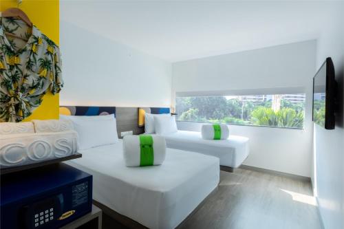 a room with two white beds and a tv at COSI Pattaya Wong Amat Beach - SHA Plus Certified in Pattaya North