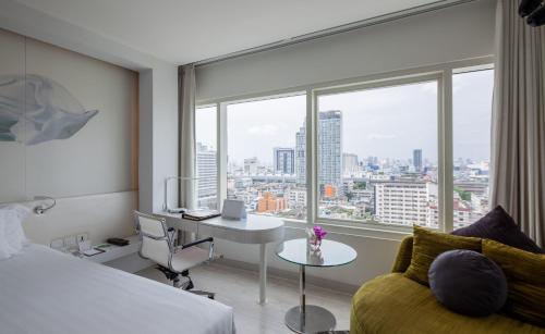 ein Hotelzimmer mit einem Bett, einem Schreibtisch und einem Fenster in der Unterkunft Centara Watergate Pavilion Hotel Bangkok in Bangkok