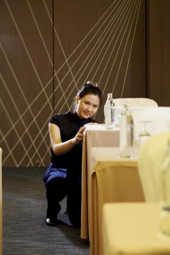 a woman sitting at a table in a restaurant at Centara Watergate Pavilion Hotel Bangkok in Bangkok