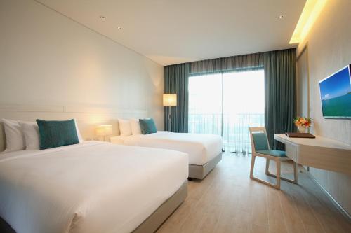 a hotel room with two beds and a desk at Centara Life Maris Resort Jomtien in Jomtien Beach