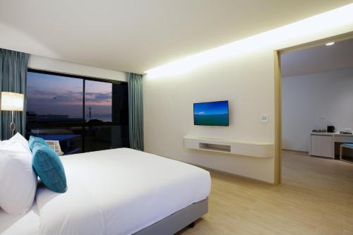 a bedroom with a white bed and a large window at Centara Life Maris Resort Jomtien in Jomtien Beach