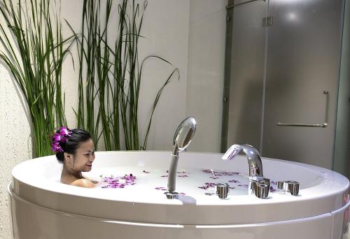 a woman in a bath tub with two faucets at Centara Life Maris Resort Jomtien in Jomtien Beach
