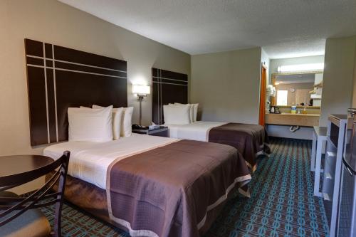 a hotel room with two beds and a table at Deluxe Inn - Fayetteville I-95 in Fayetteville