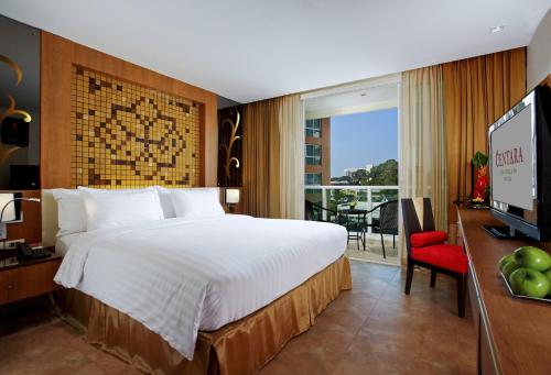 Habitación de hotel con cama grande y TV en Centara Nova Hotel Pattaya en Pattaya centro