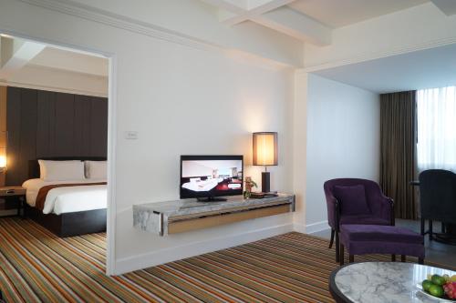 a hotel room with a bed and a flat screen tv at Centara Hotel Hat Yai in Hat Yai