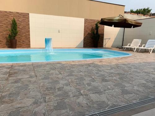 a swimming pool with a fountain and an umbrella at Casa com piscina in Porto Belo