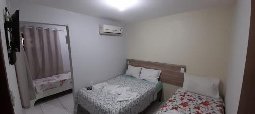 a small bedroom with two beds and a mirror at Pousada Mandacaru in Maceió