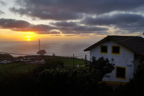 a house on a hill with the sunset in the background at Sunset Nest in Ponta Delgada