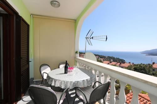 a table and chairs on a balcony with a view of the ocean at Greenhouse family apartments in Rabac