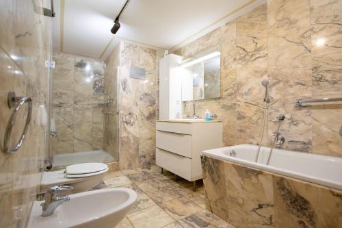a bathroom with a tub and a toilet and a sink at Central City Villa in Neuss